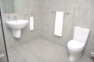 Un bagno moderno con lavandino, water e portasciugamani bianchi.