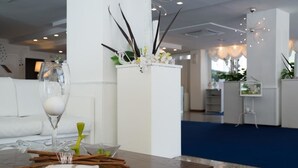 Un vestíbulo de hotel moderno con una mesa de centro de madera, una columna blanca con plantas decorativas y una alfombra azul.
