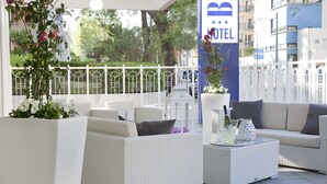 Un vestíbulo de hotel con muebles de mimbre blanco, una cerca blanca y un letrero que dice "HOTEL".