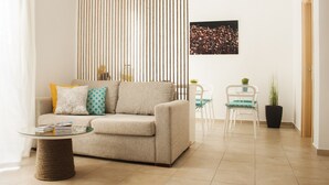 A modern living room with a beige sofa, a glass coffee table, and a striped partition. - Krinis Apartments (Rhodes)