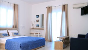 A hotel room with a bed, a desk, a chair, a TV, and a sofa. - Krinis Apartments (Rhodes)