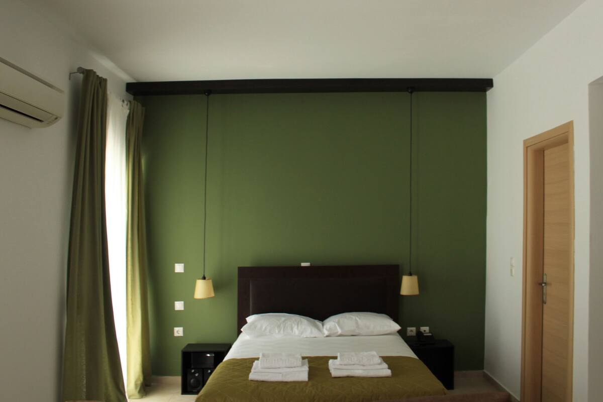 A hotel room with a bed, two bedside lamps, a nightstand, and a wooden door.