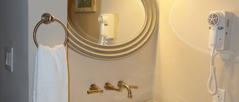Un baño con lavabo, espejo, toallero y secador de pelo montado en la pared.