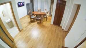 Un'area pranzo con un tavolo e sedie in legno, una televisione a parete e una porta con attaccapanni.