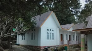 A white building with a gabled roof and a porch. There are two motorcycles parked in front. - Hostel Roma Inn 2 (Kalaw)