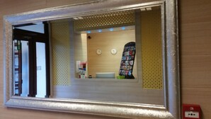 Ein Badezimmer mit Spiegel, Waschbecken, einer Uhr und einem Zeitschriftenständer.