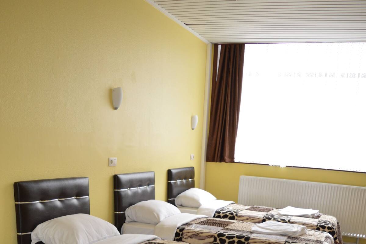A hotel room with two beds, each with a headboard and white bedding.