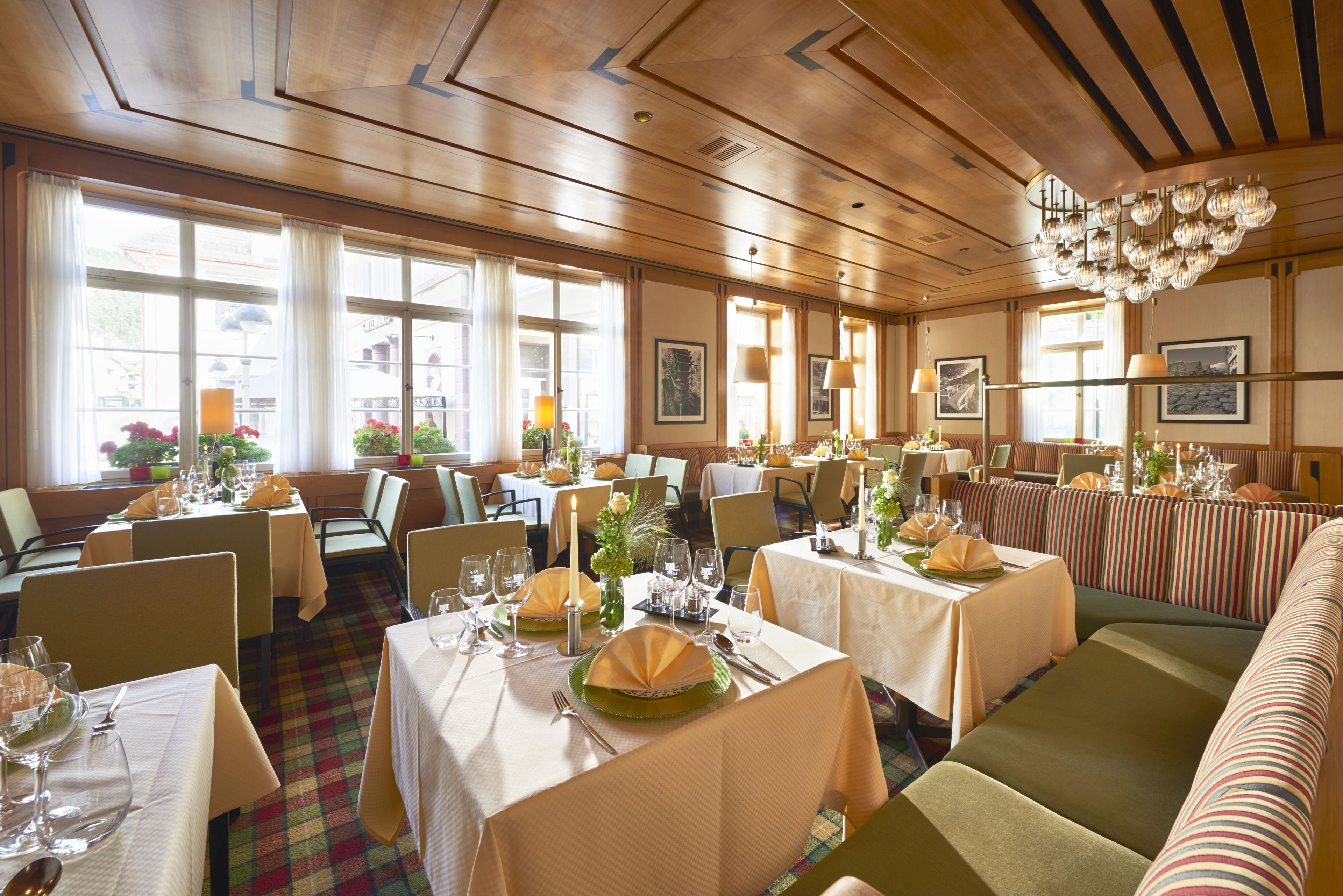 Un restaurante con varias mesas y cabinas, techo de madera y grandes ventanales.
