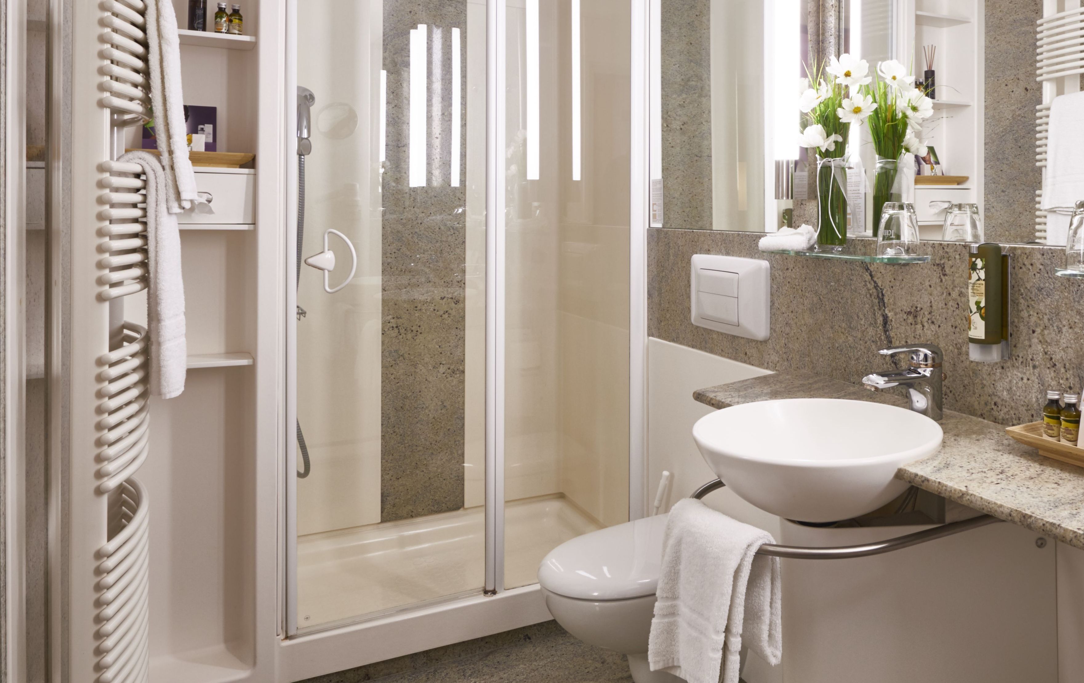 Un bagno moderno con doccia vetro, lavabo bianco e water.