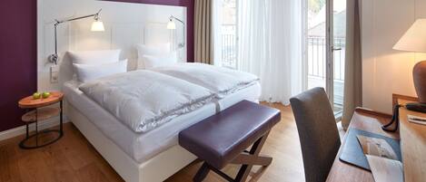 Une chambre d’hôtel moderne avec un grand lit, un bureau et une vue sur l’extérieur.