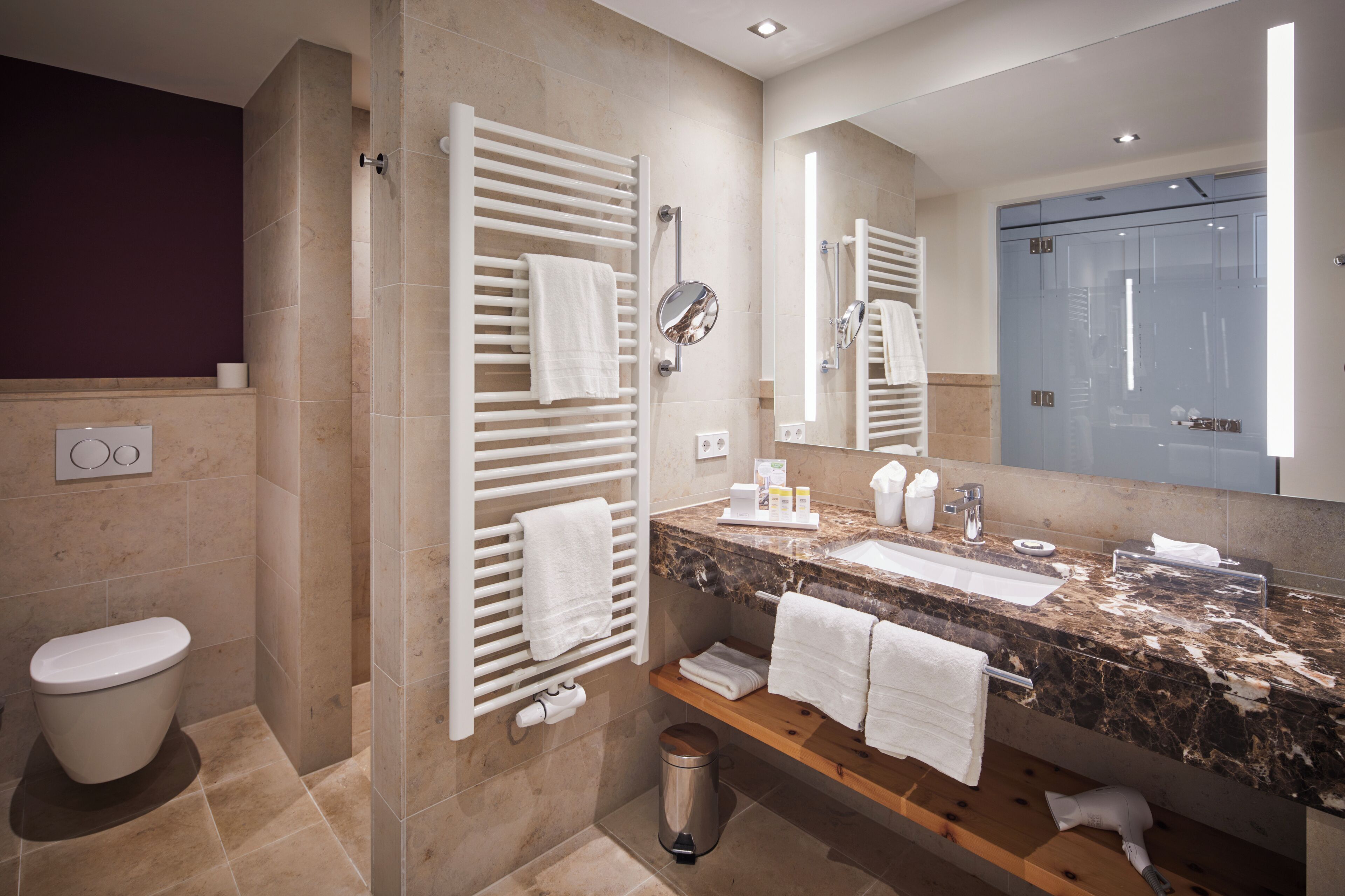 Ein modernes Badezimmer mit Marmorplatte, integriertem Waschbecken, großem Spiegel und Duschbereich mit Glastür.