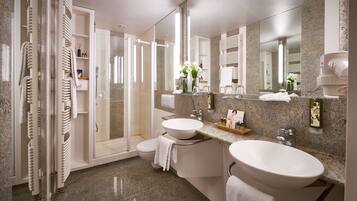 A modern bathroom with a glass-enclosed shower, two sinks, and a large mirror.