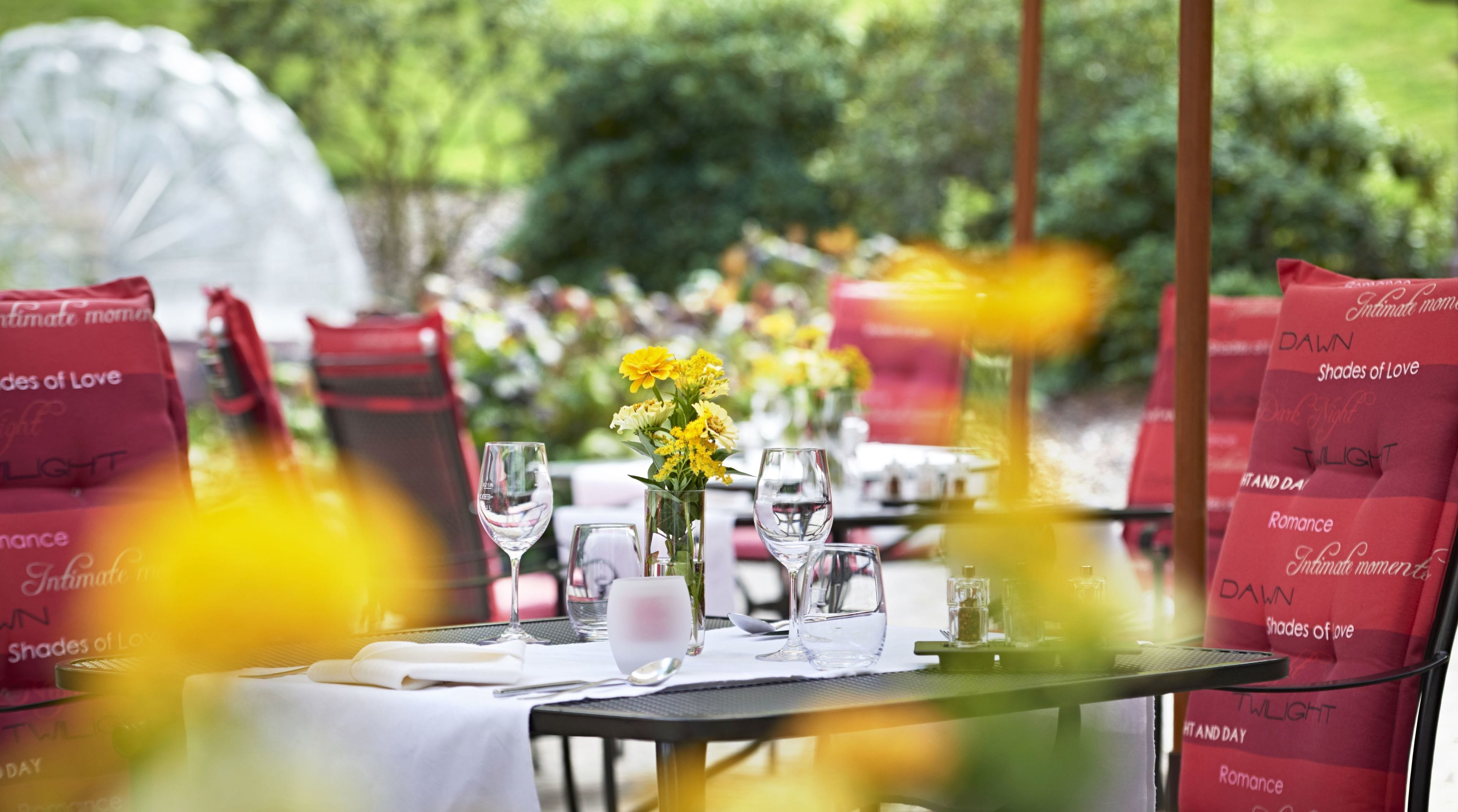 A table set for dining with a clear view of the tablecloth, glassware, and a vase with yellow flowers.