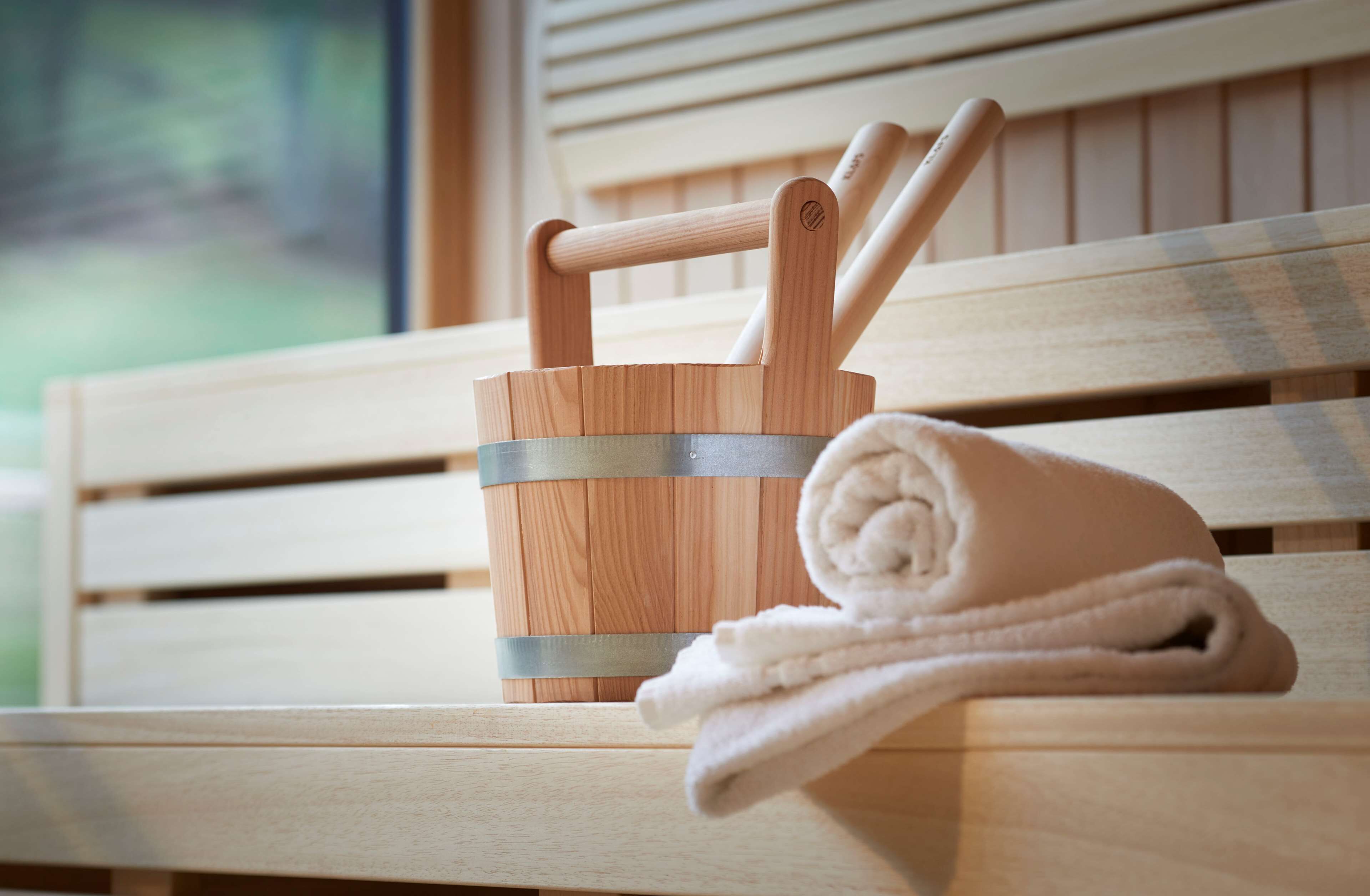 Un banco de madera con una toalla y un recipiente de madera que contiene dos palos de madera.