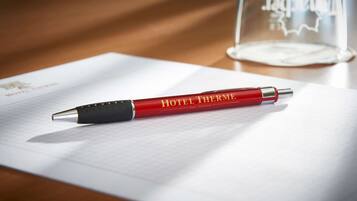 Una penna rossa con la scritta "HOTEL THERME" posata su un foglio di carta millimetrata.