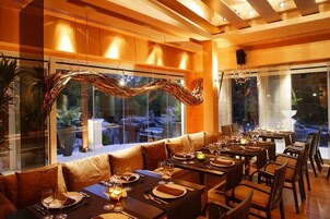 Un restaurante con una larga mesa de comedor, asientos acolchados y vistas al exterior.