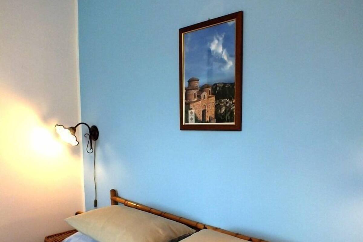 Un lit avec une tête de lit en bois, deux oreillers et un luminaire fixé au mur.