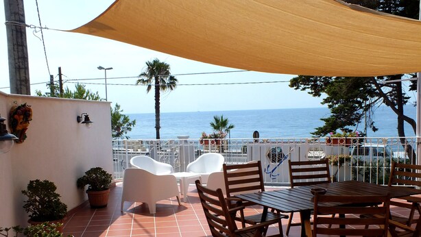 Une terrasse avec une table et des chaises, des plantes en pot et une vue sur la mer.