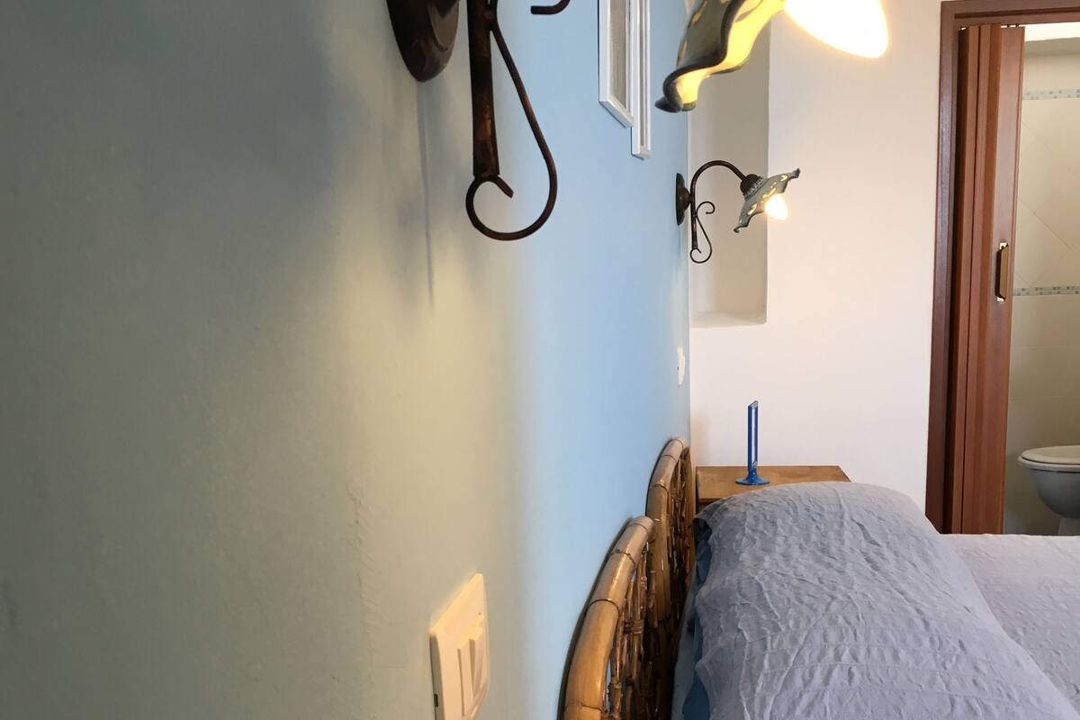 Une chambre à coucher avec un lit en bois, une table de chevet et des lampes fixées au mur.