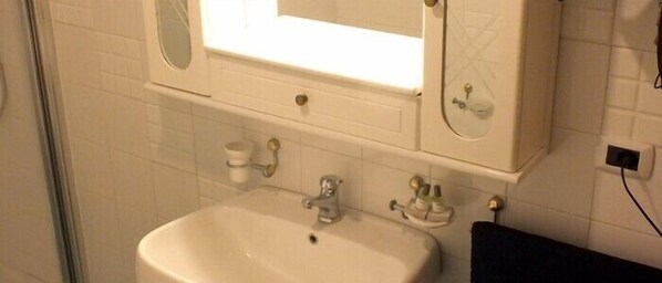 A bathroom with a white sink, a mirror above it, and a towel rack to the right.