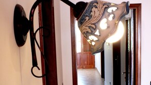 Un couloir avec un luminaire fixé au mur et une porte donnant sur une autre pièce.