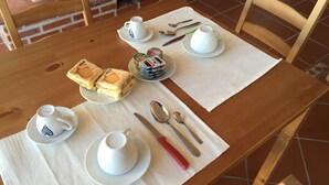 Une table en bois, dressée avec des assiettes, des tasses et des couverts blancs, sur laquelle on a disposé des sandwichs et des condiments sur un set de table.