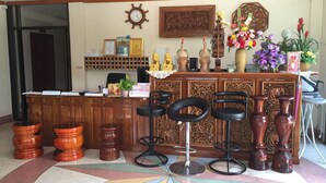 A reception area with a wooden desk, black chairs, a clock, framed pictures, and a floral arrangement. - The Star Hotel (Udon Thani)
