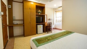 A bedroom with a bed, a wooden wardrobe, a small refrigerator, a television, and a desk with a chair. - The Star Hotel (Udon Thani)