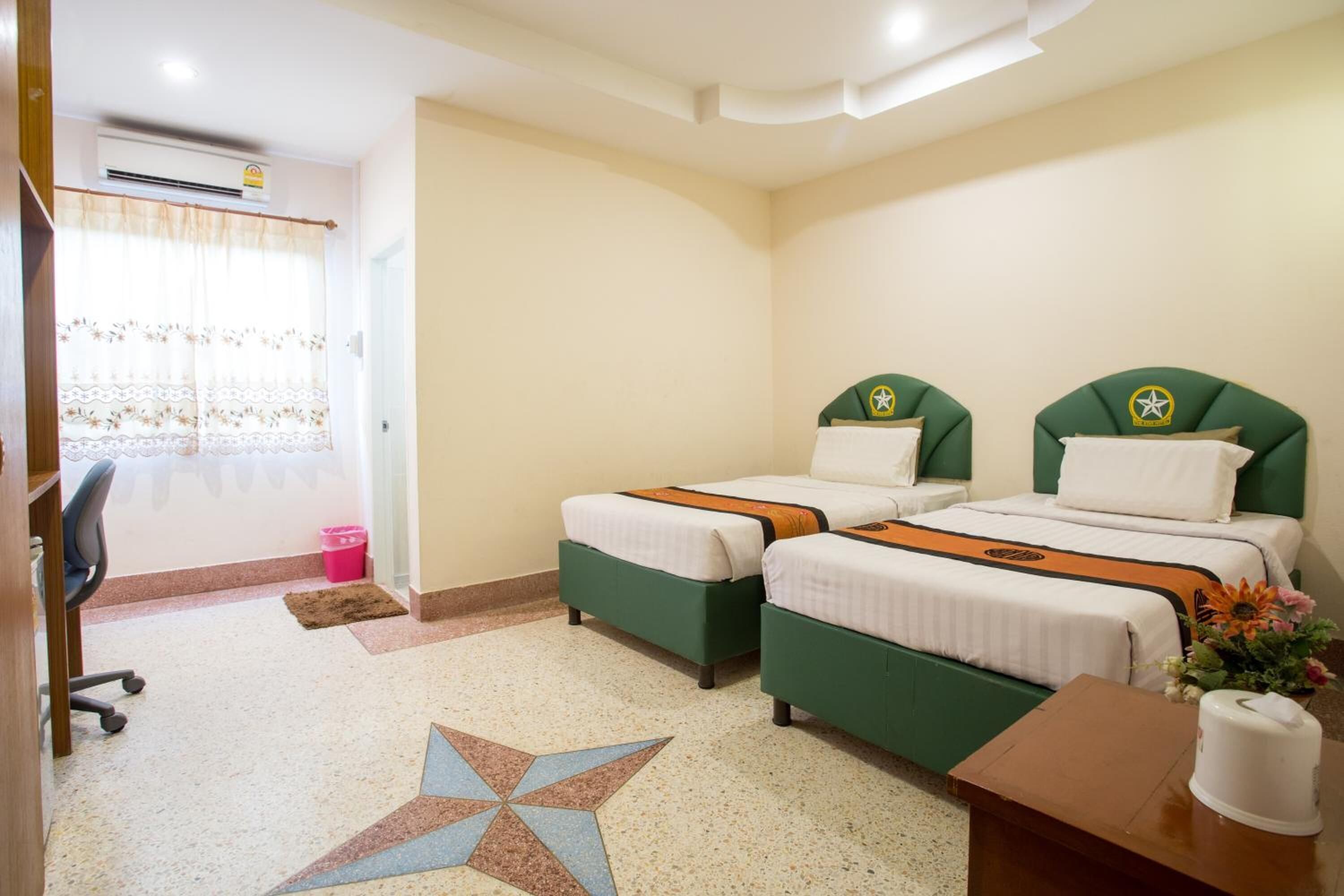 Una habitación de hotel con dos camas, un escritorio, una silla y una ventana con cortinas.