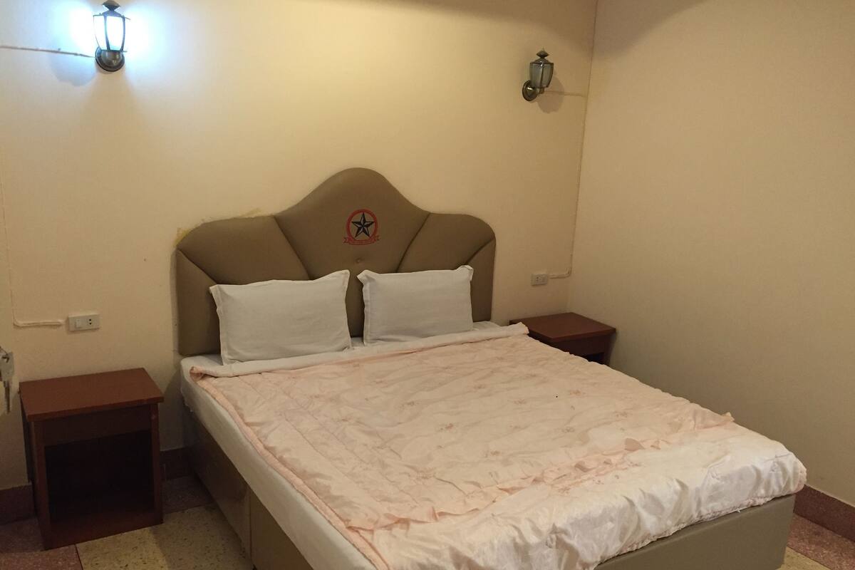 A bedroom with a bed, two bedside tables, and wall-mounted lamps.