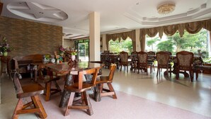 A spacious dining area with a brick wall, wooden chairs, and a large table. - The Star Hotel (Udon Thani)