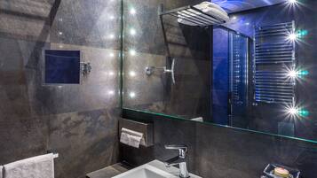 Een moderne badkamer met een douche met glazen wand, een witte wastafel en een handdoekrek.