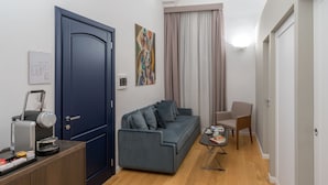 Una sala de estar moderna con una puerta azul oscuro, un sofá gris, una cafetera y un cuadro en la pared.