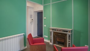 Una habitación con paredes verdes, una chimenea y dos sillas rojas.