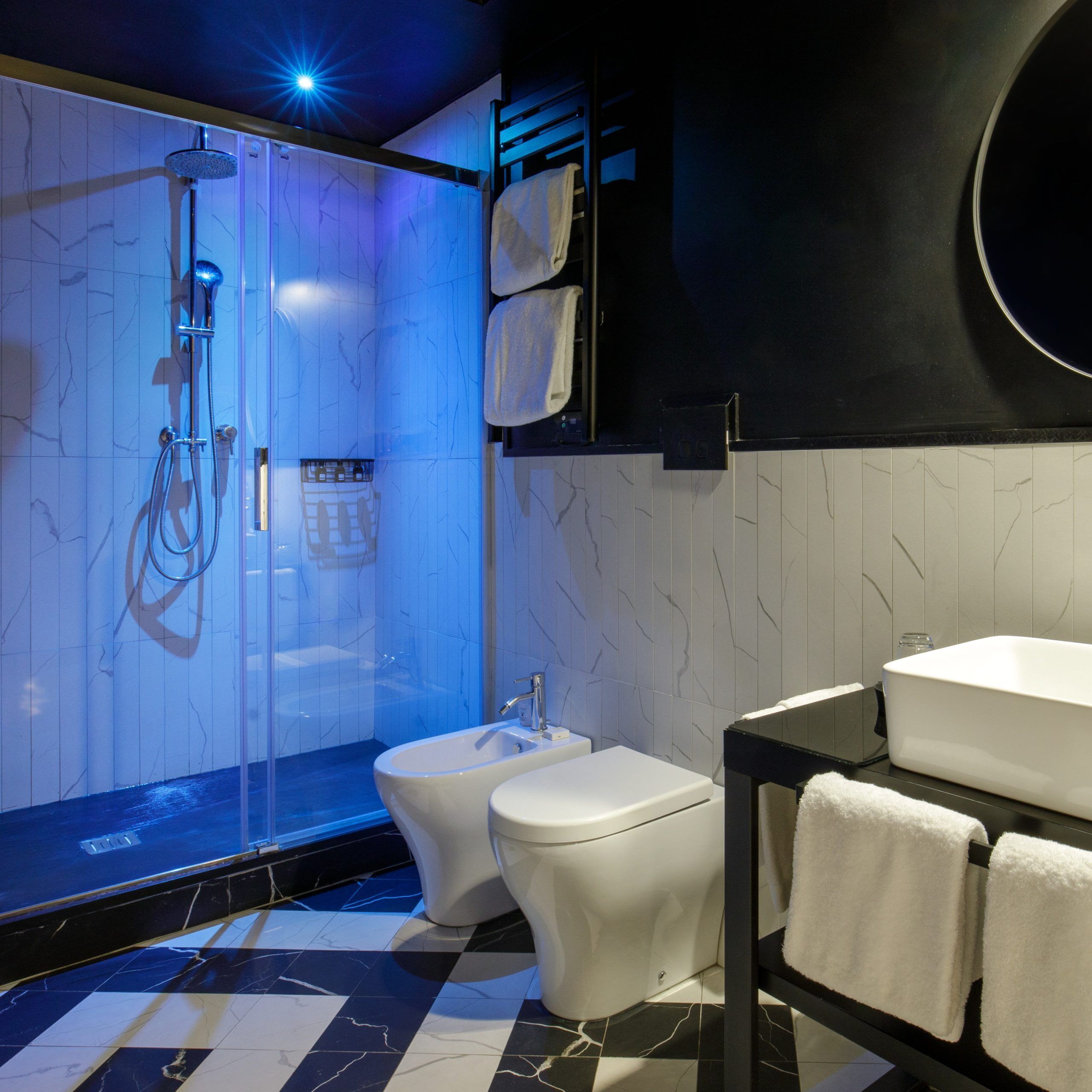 A modern bathroom with a glass-enclosed shower, a toilet, and a sink.