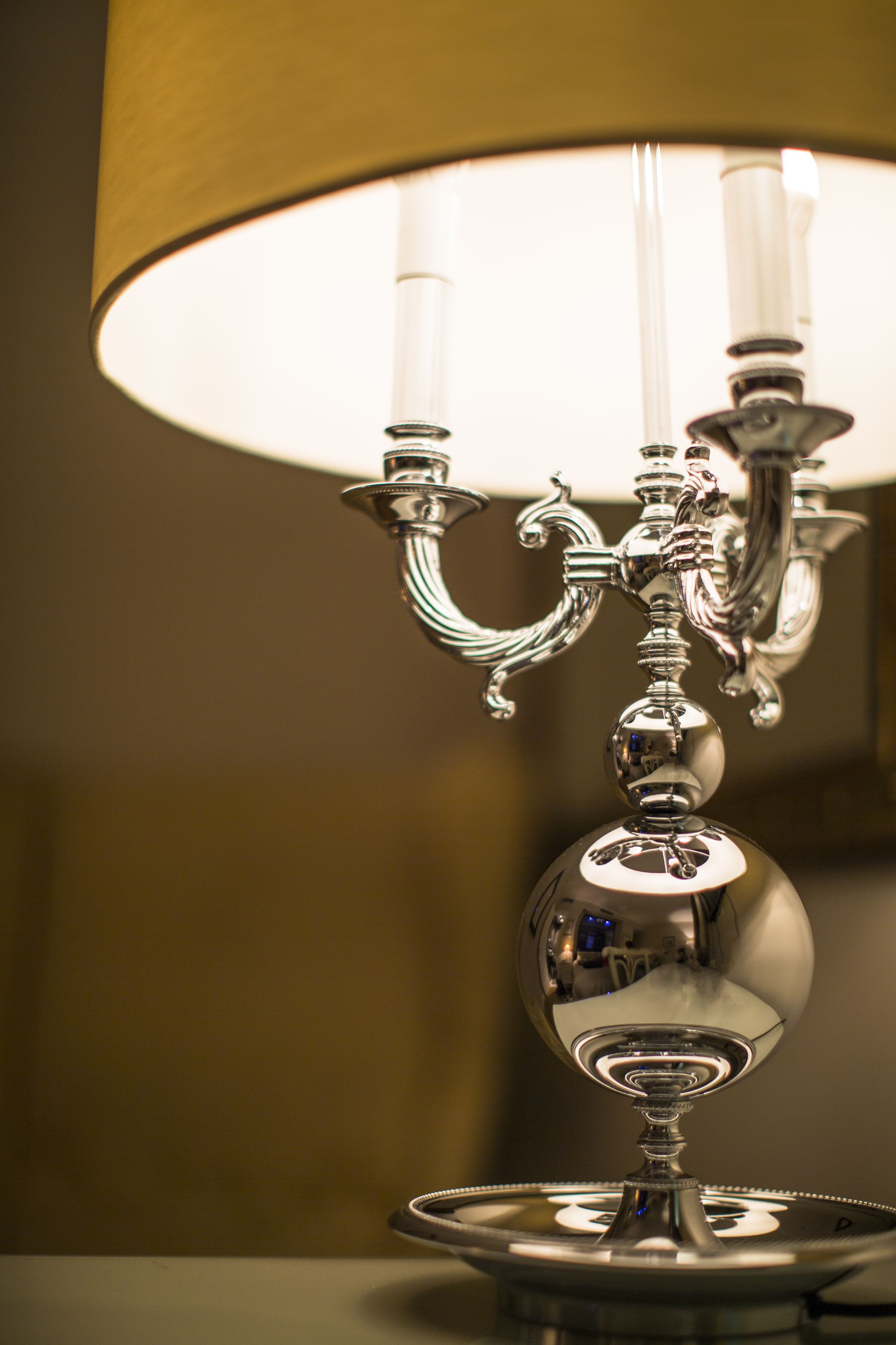 A chandelier with a reflective surface and a lampshade.