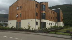 Een modern gebouw met een houten gevel, meerdere ramen en een plat dak.