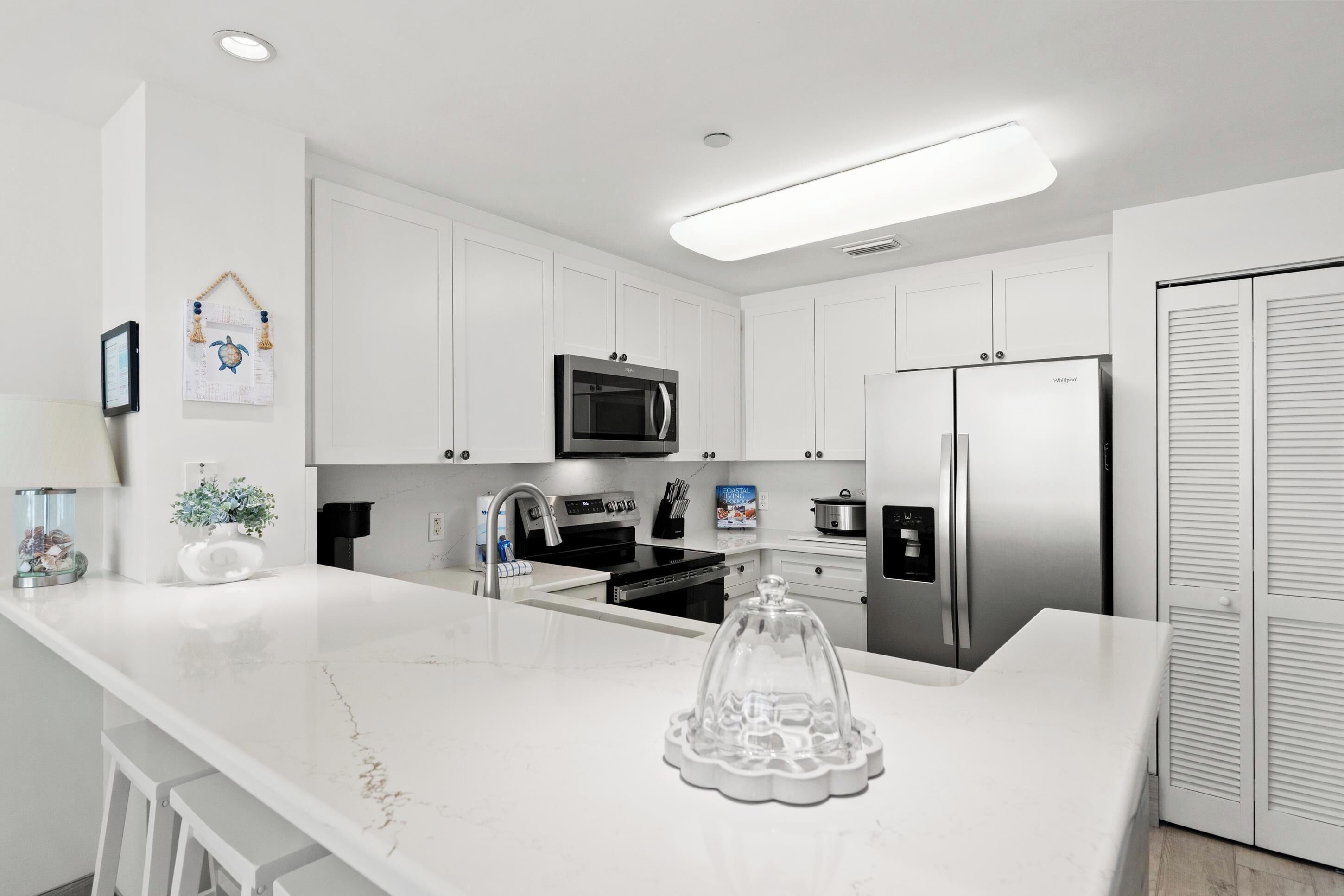 A modern kitchen with white cabinetry, a stainless steel refrigerator, a microwave, and a built-in oven.