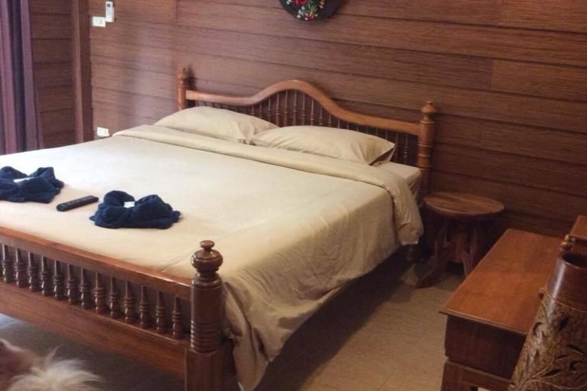A wooden bed with a headboard, a bedside table, and a small stool.