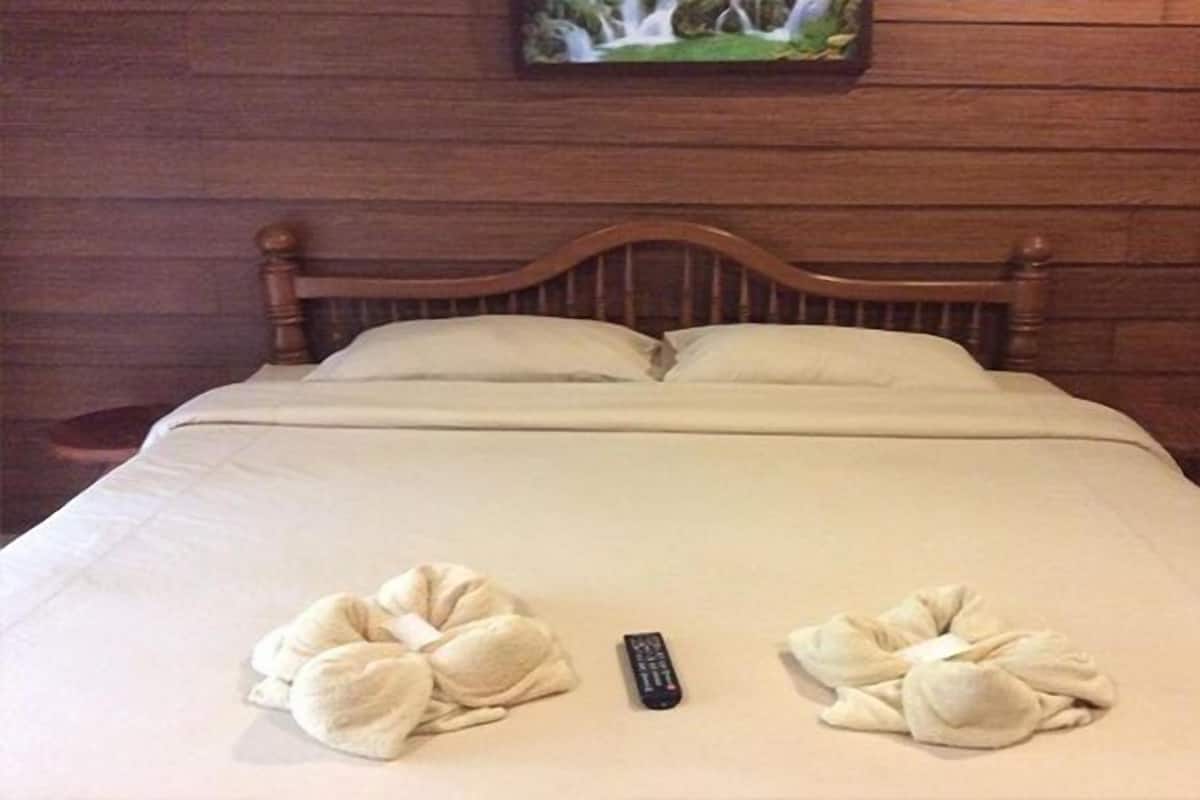 A neatly made bed with two towels and a remote control on the bed.