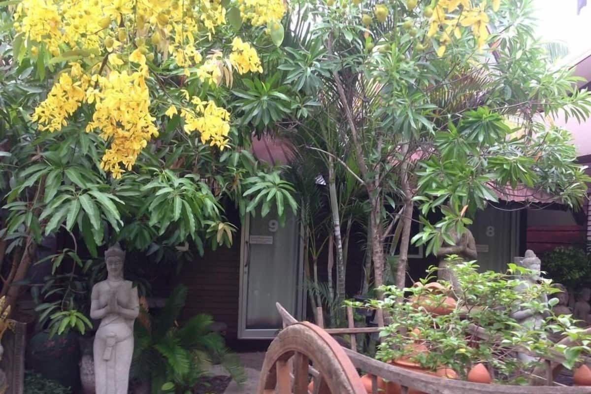 A garden with a statue, potted plants, and a wooden cart.