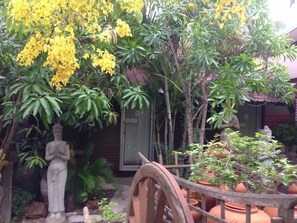 A garden with a statue, potted plants, and a wooden cart. - Country View Resort (Udon Thani)