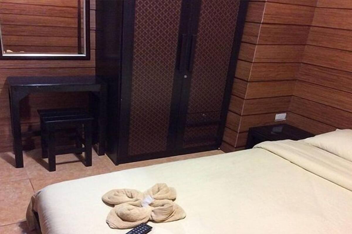 A hotel room with a bed, a small table, a chair, and a wardrobe.