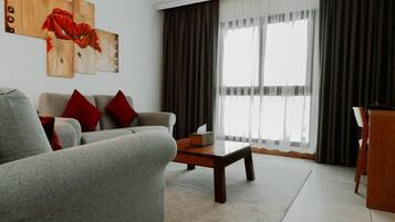 A living room with a grey sofa, red cushions, a wooden coffee table, and a painting on the wall.