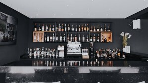 A bar area with a marble countertop, shelves of liquor bottles, and a coffee machine. - Star Land Hotel Bonapriso (Douala)