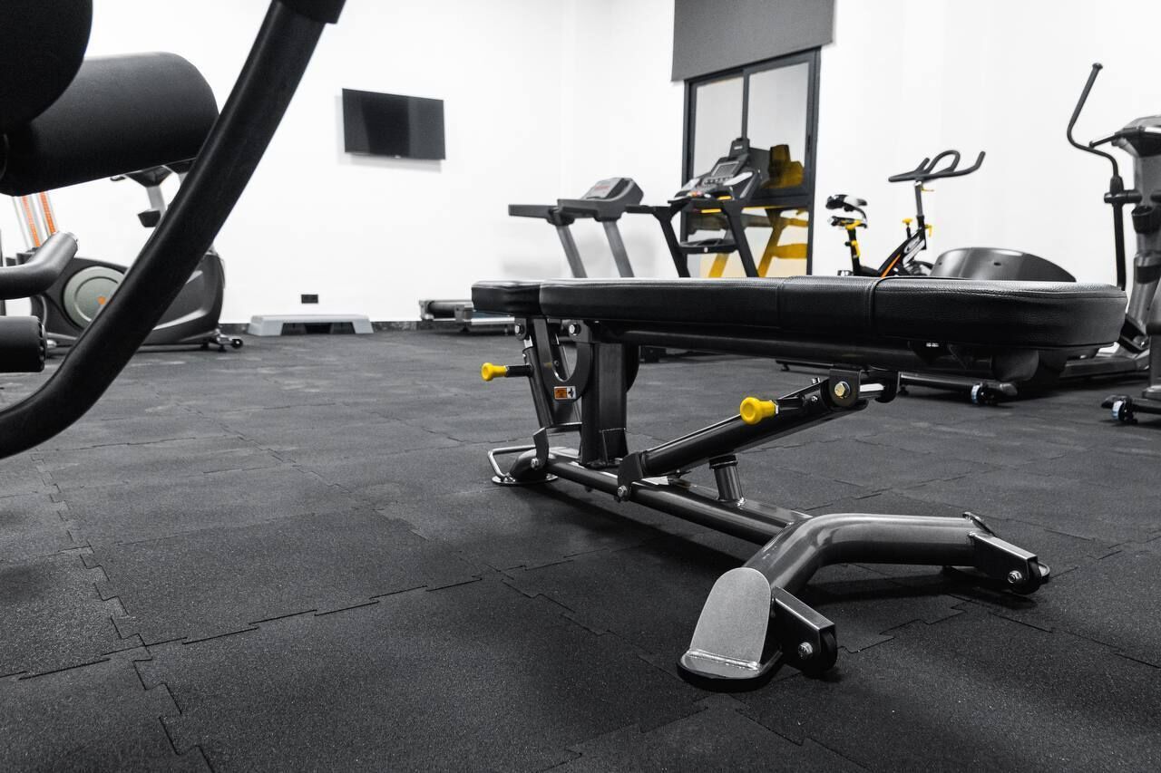 A gym with exercise equipment including a bench, weight bench, and stationary bikes.