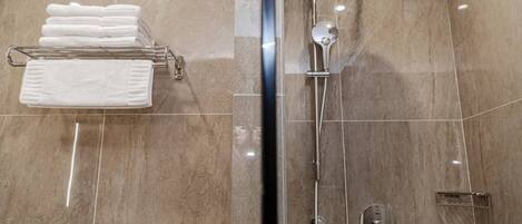 Un baño moderno con ducha de vidrio, un perchero con toallas dobladas y un panel de control en la pared.