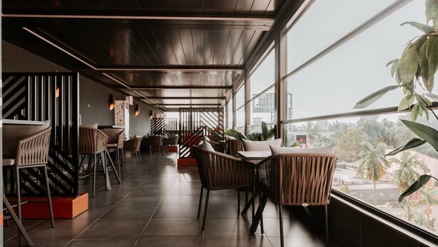 A spacious indoor area with high ceilings, large windows, and modern furniture. - Star Land Hotel Bonapriso (Douala)