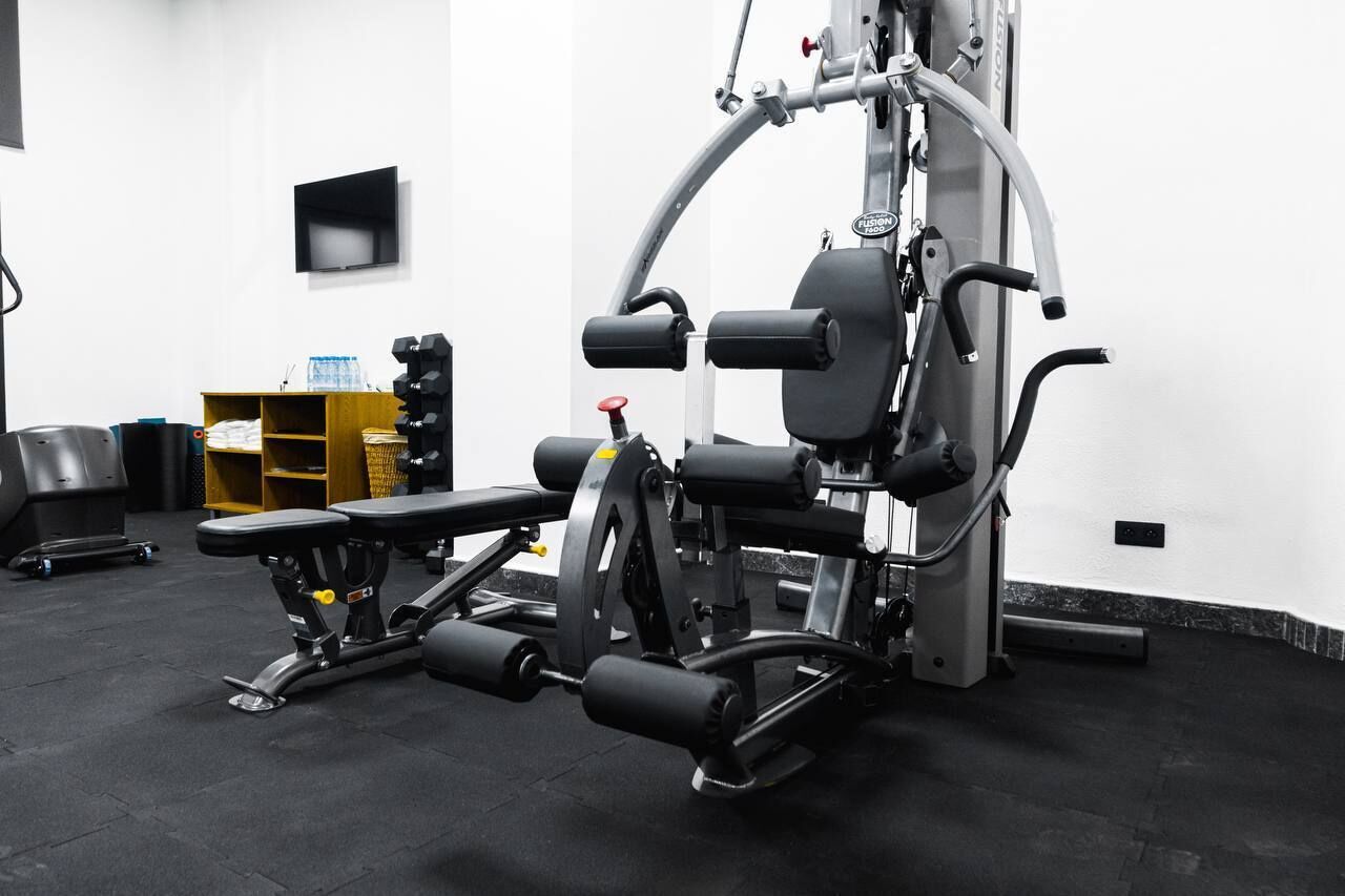 A gym with a bench press, weight stack, and various exercise machines.