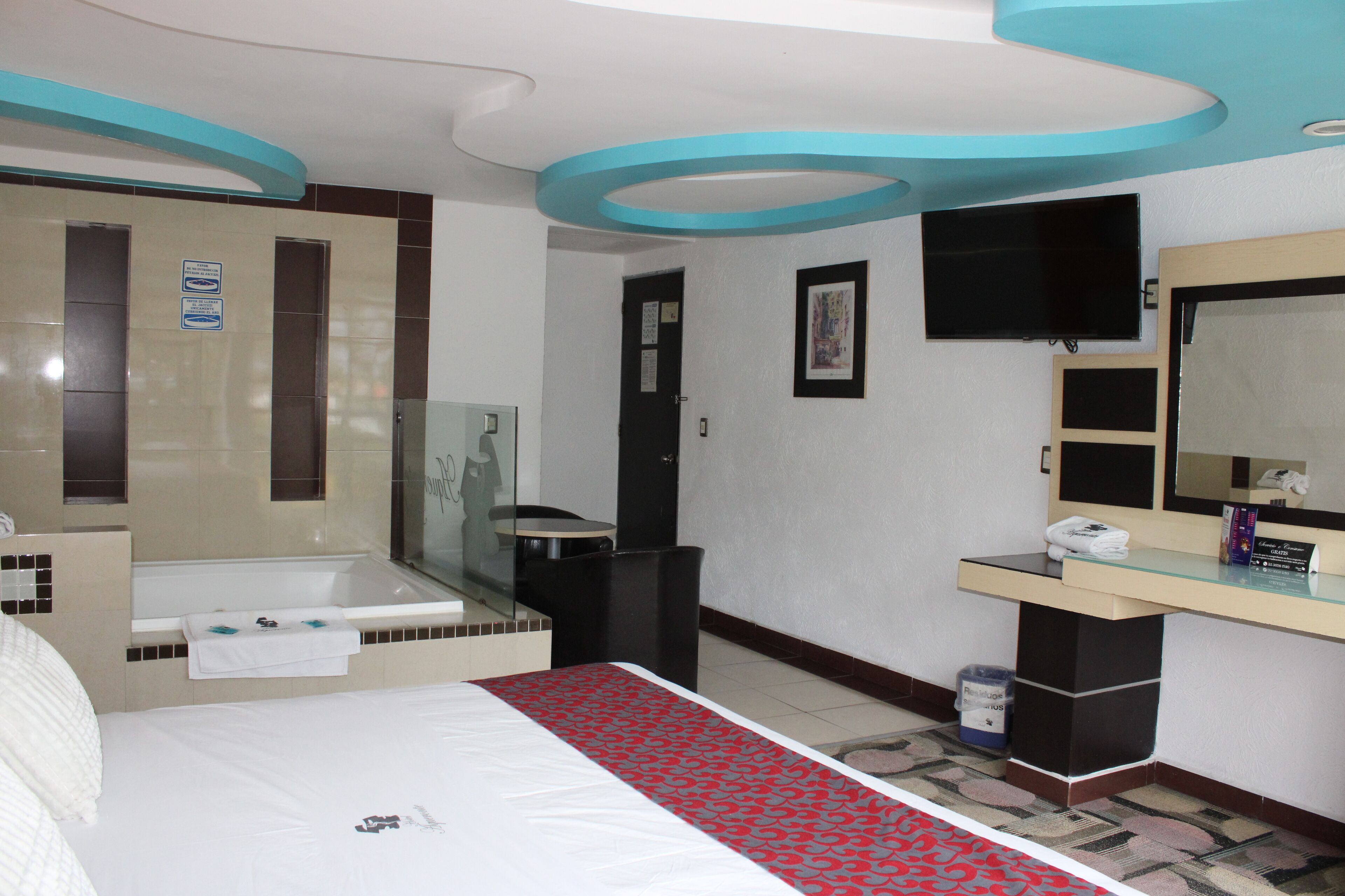 Habitación de hotel con cama, baño con bañera, lavamanos y espejo.